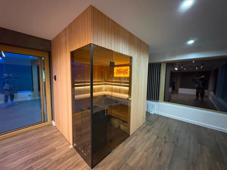 Nowoczesna sauna do domu na wymiar z drewnianą zabudową i szklanymi drzwiami